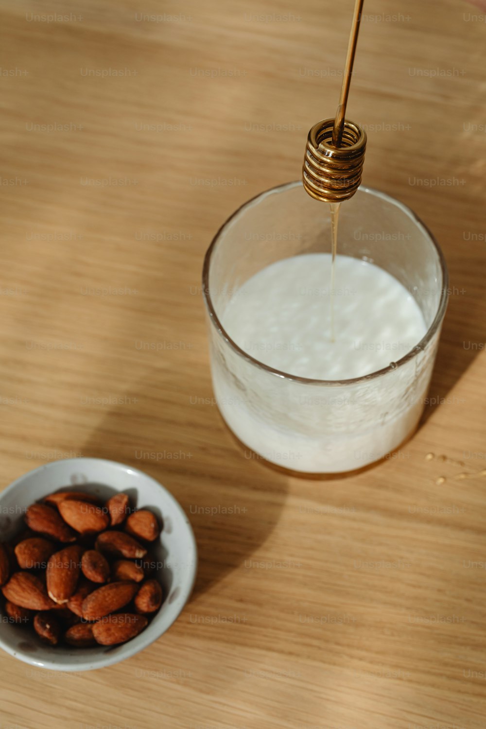 a bowl of almonds next to a glass of milk