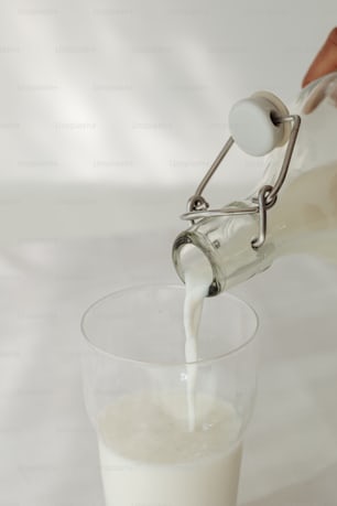 a person pouring milk into a glass