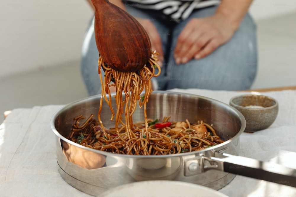 a woman is pouring noodles into a pan