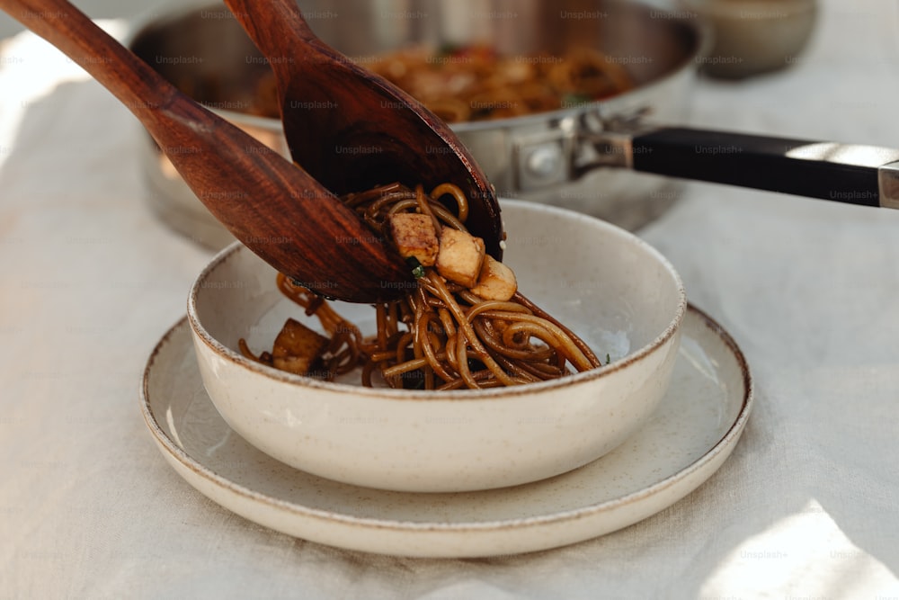 a bowl of noodles with a wooden spoon in it