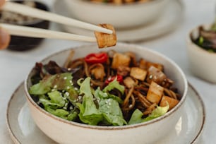 a bowl of food with chopsticks sticking out of it