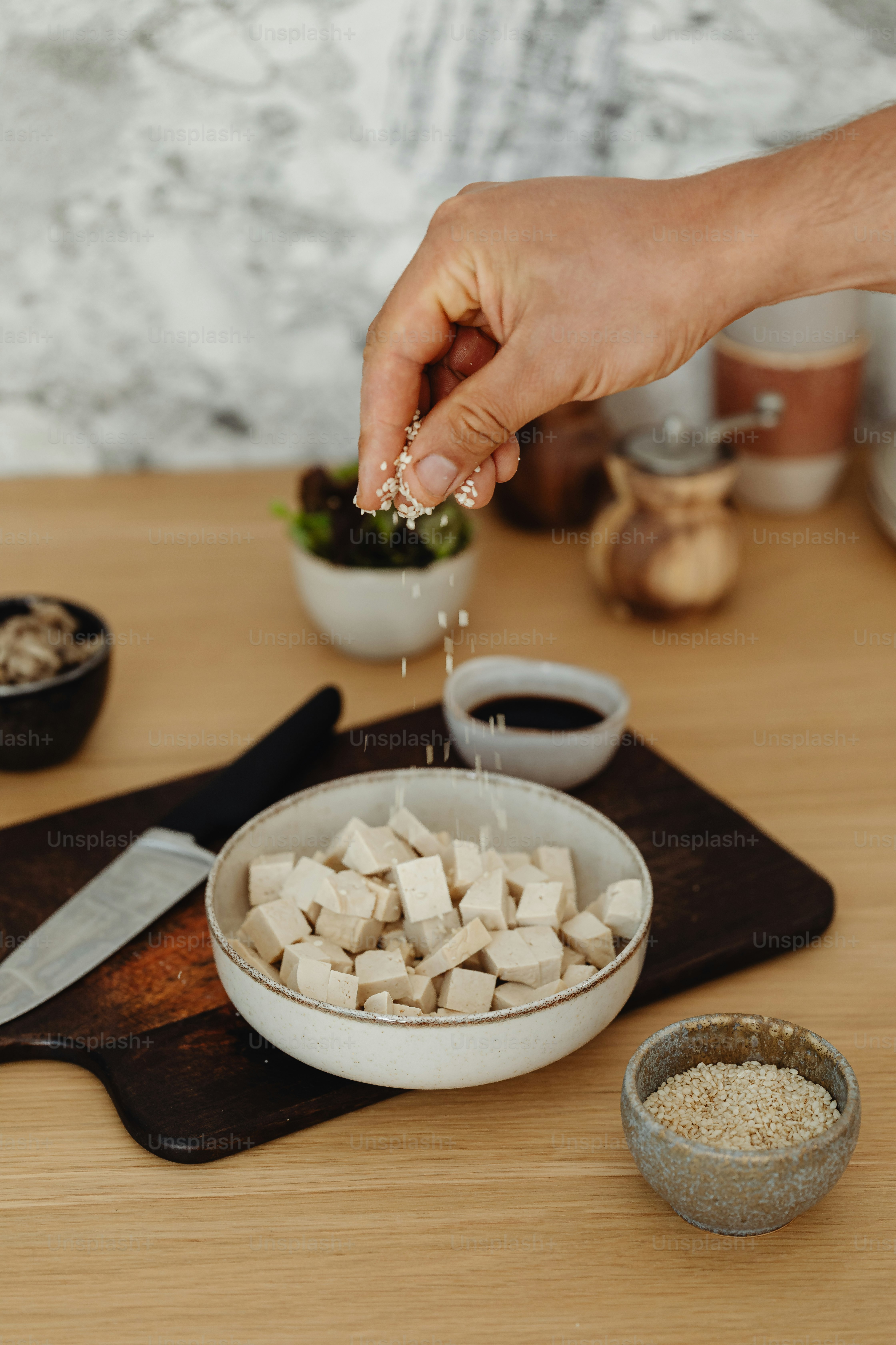 a person sprinkling sugar over a bowl of tofu