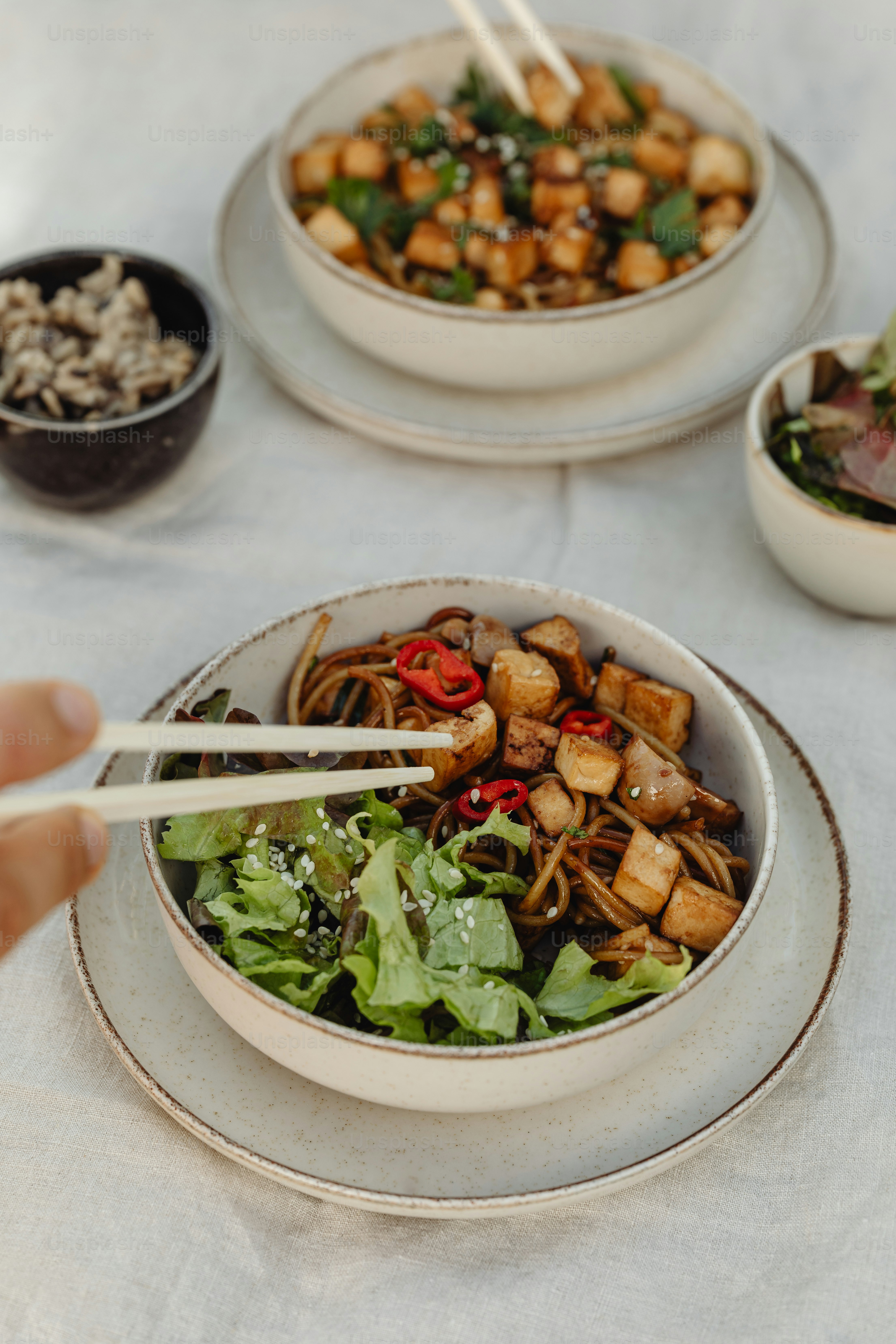 a person holding chopsticks over a bowl of food
