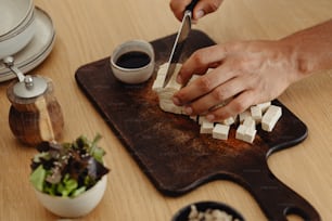 a person cutting up cubes of food on a cutting board