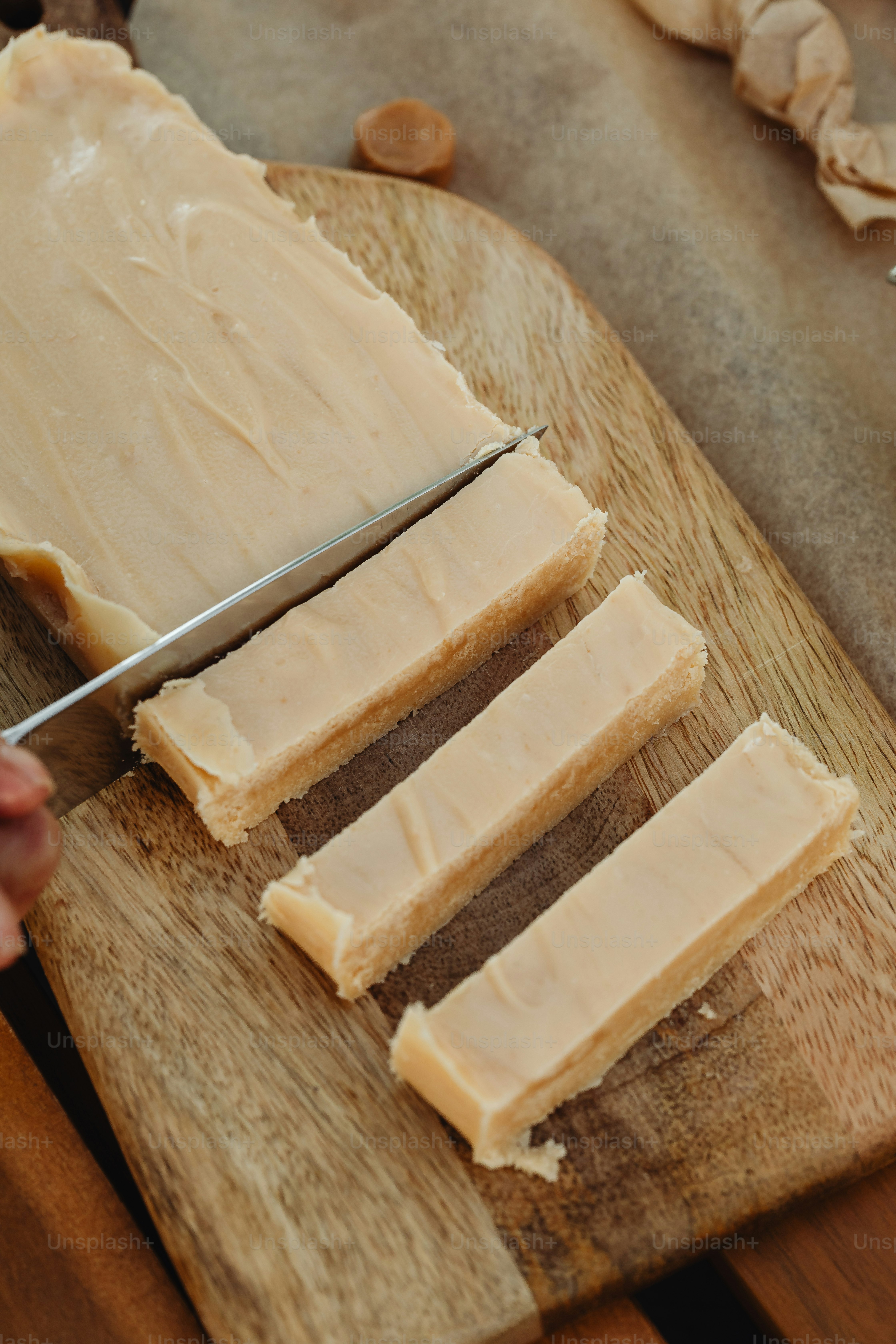 a person cutting a piece of bread on a cutting board