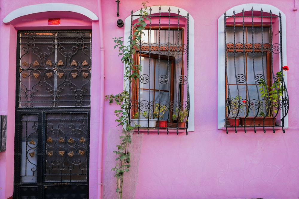 a pink building with two windows and a black door