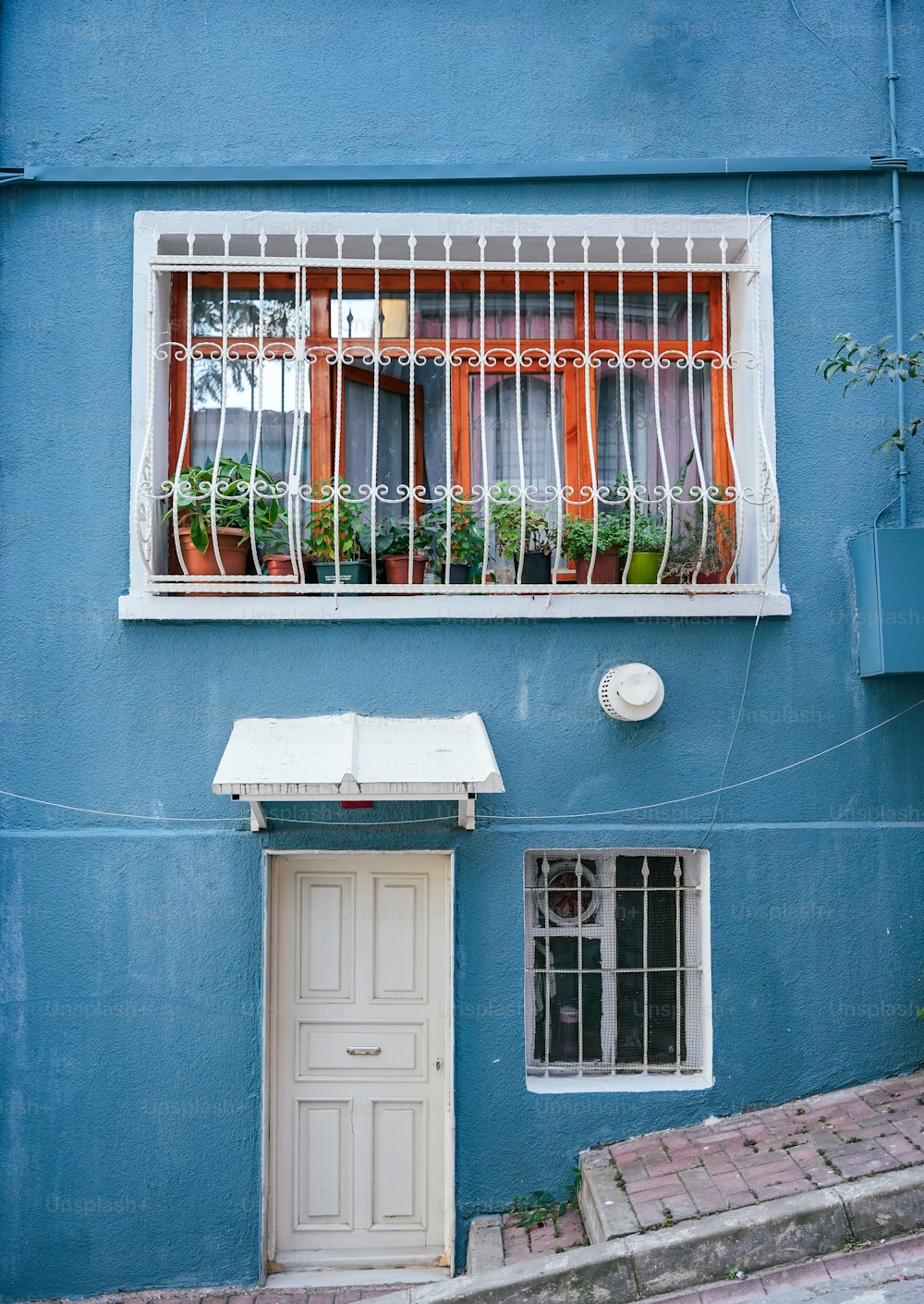 Ein blaues Gebäude mit weißer Tür und weißem Fenster