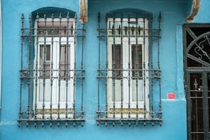 um edifício azul com duas janelas e barras de ferro