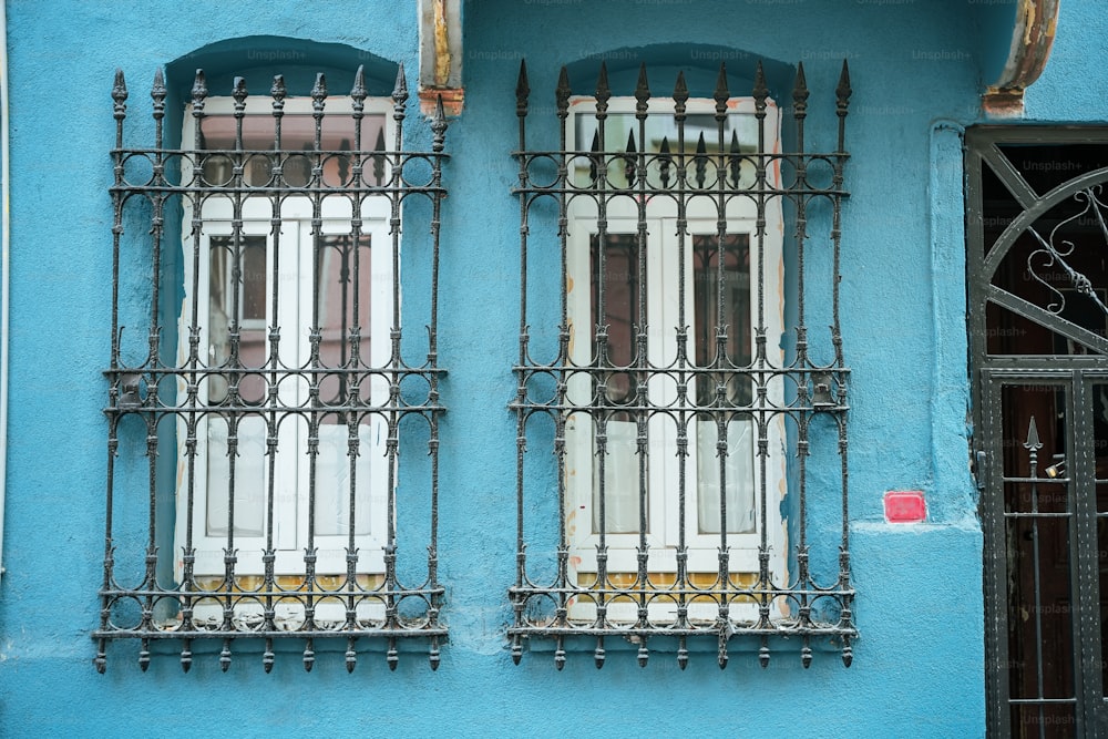 a blue building with two windows and iron bars