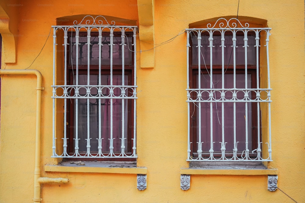 ein gelbes Gebäude mit zwei Fenstern und Gittern