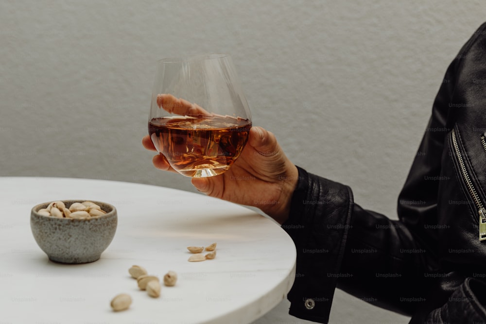 Una persona sosteniendo una copa de vino sobre una mesa