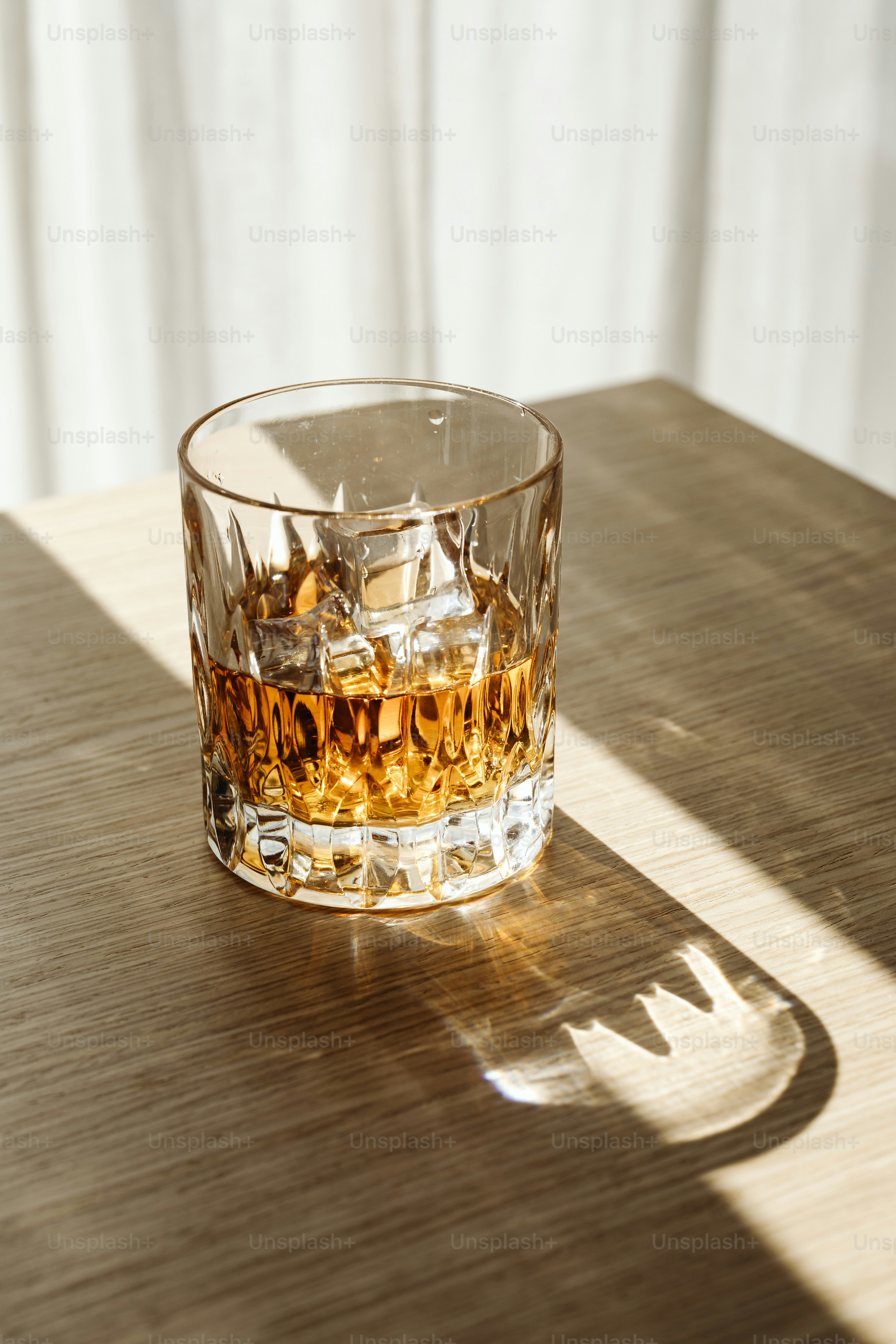 a glass of whiskey sitting on top of a wooden table