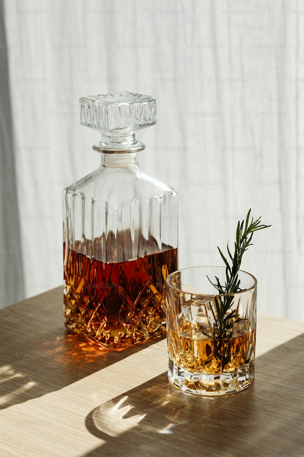 a glass of whiskey and a decanter on a table