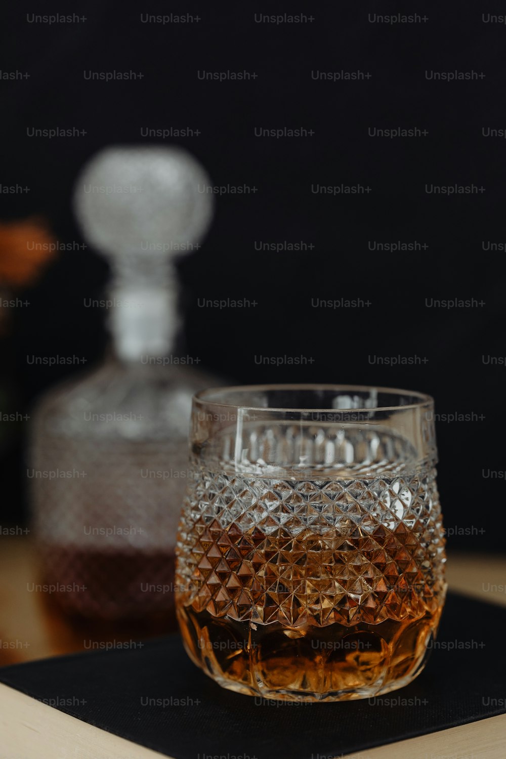 Un vaso de whisky sentado encima de una mesa de madera