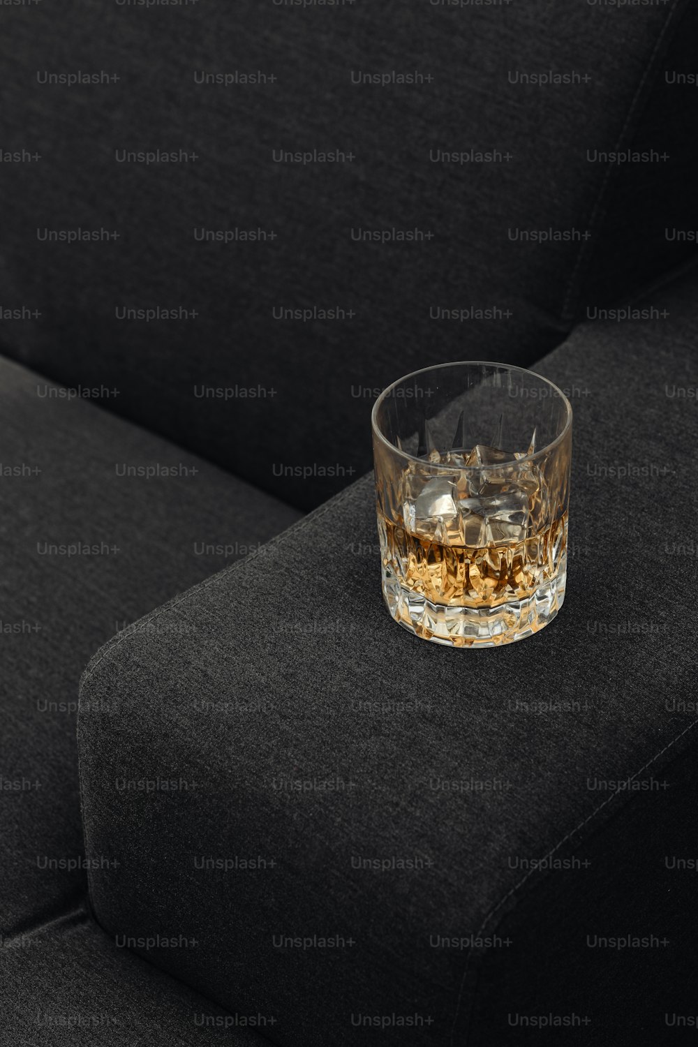 a glass of whiskey sitting on top of a couch