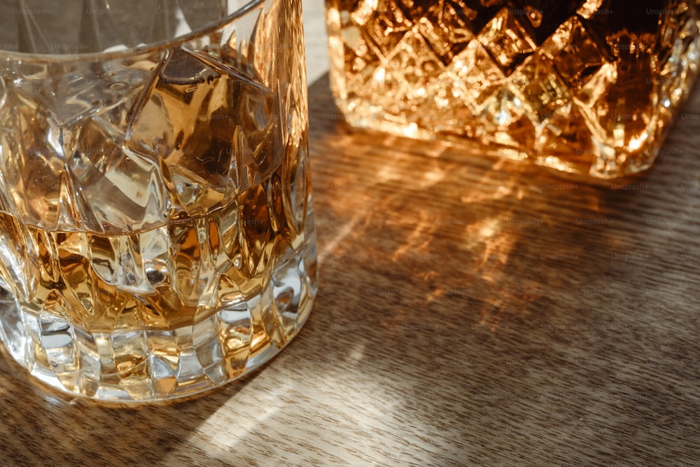 a glass of whiskey sitting on a table next to another glass