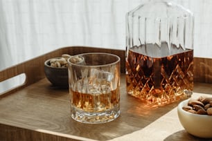 a bowl of nuts and a glass of whiskey on a table