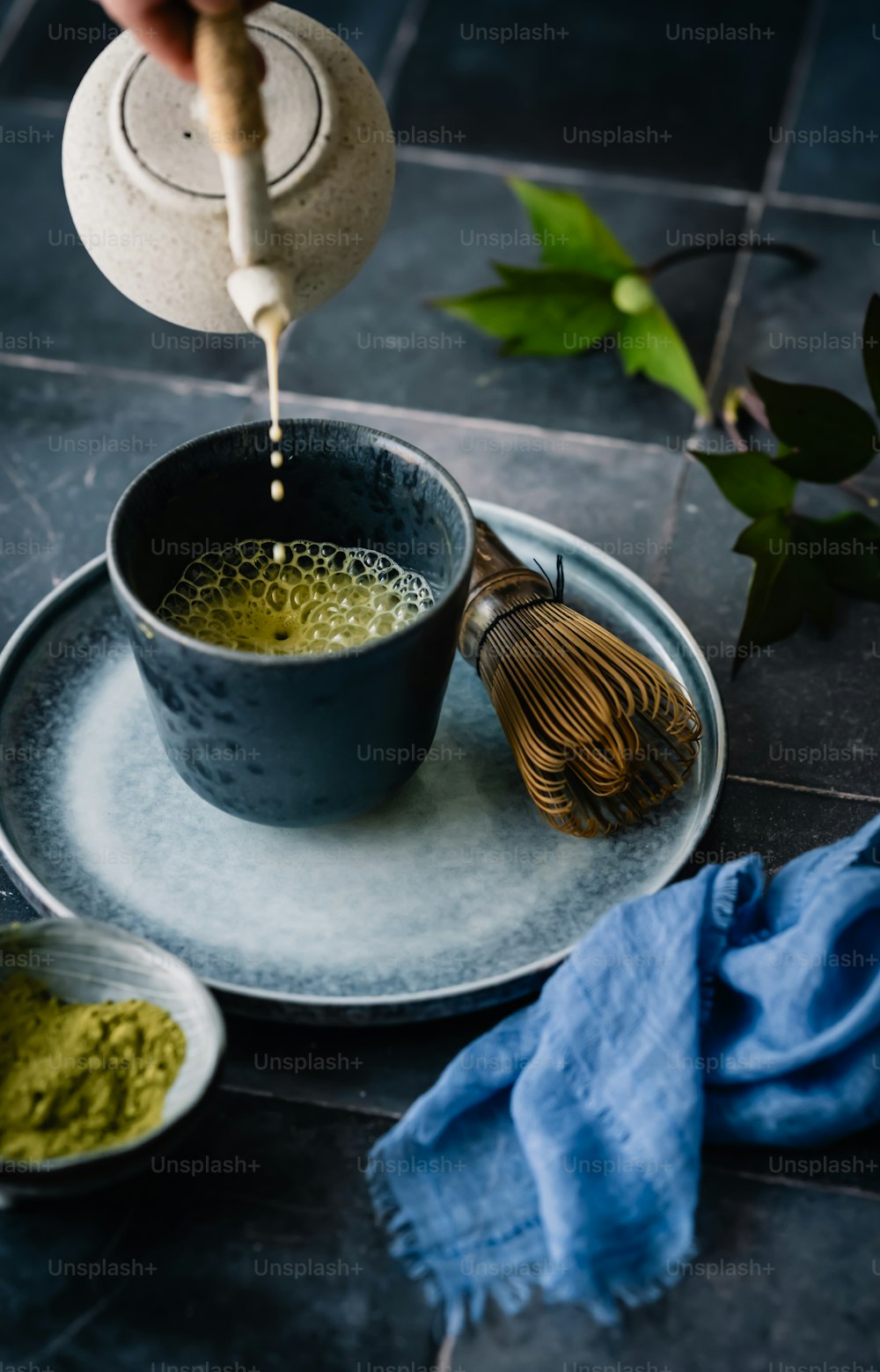 a person pouring a whisk into a cup of green tea