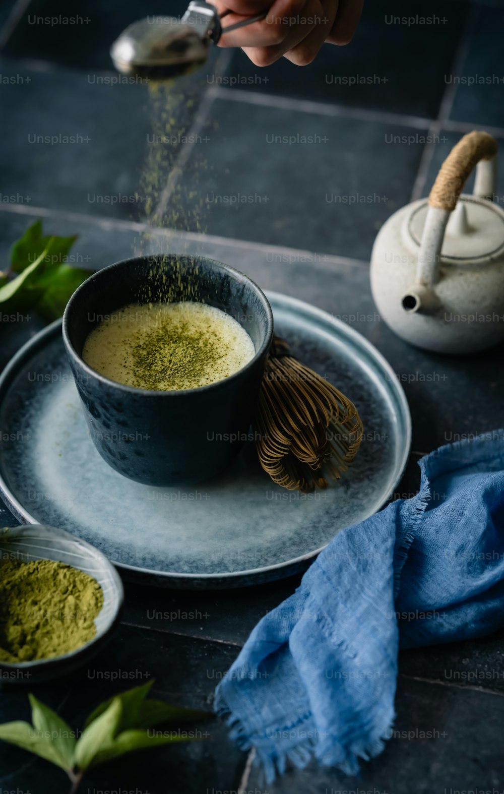 a person sprinkling green tea into a cup