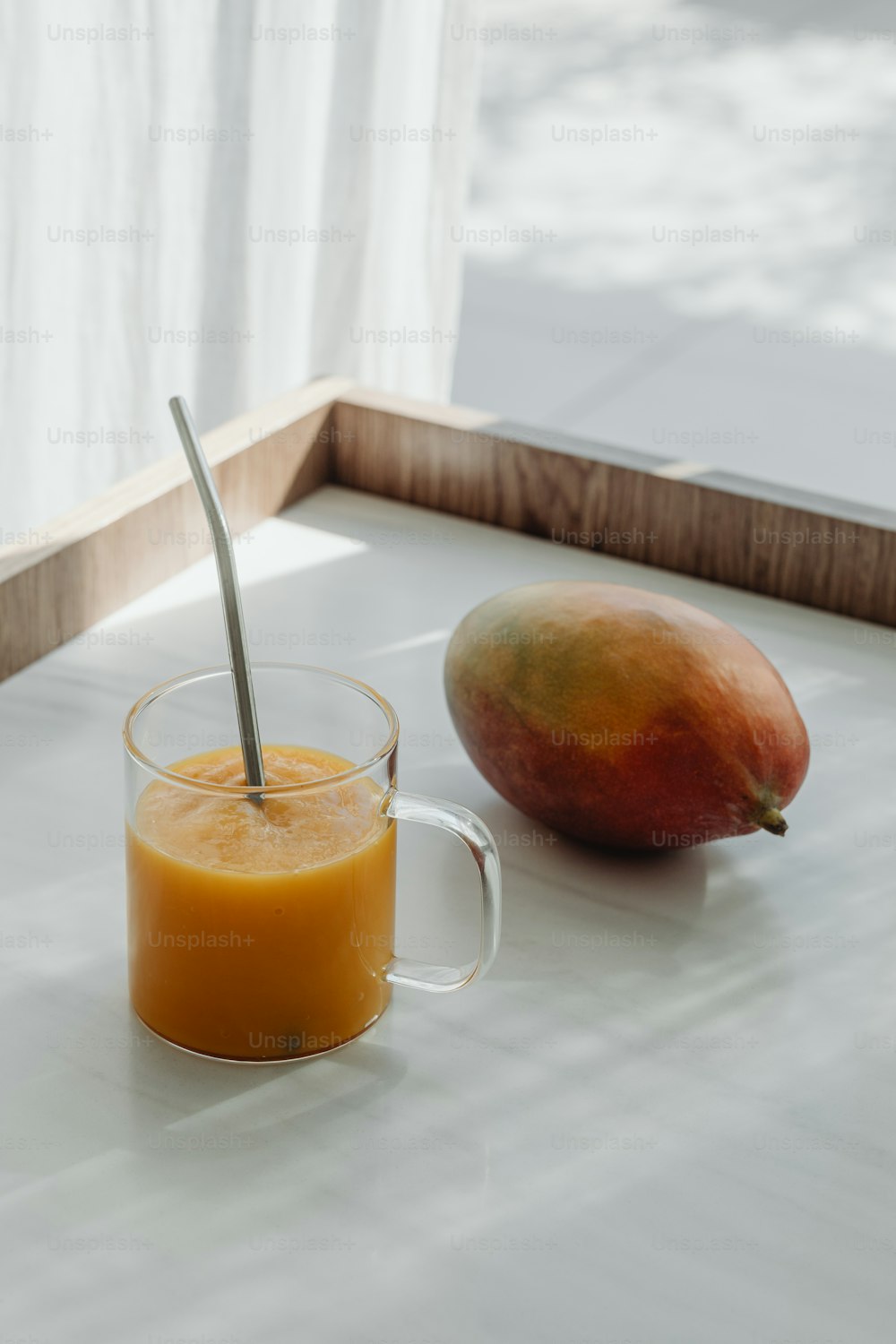 a glass of orange juice next to a mango