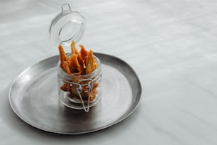 a glass jar filled with cheetos sitting on top of a metal plate