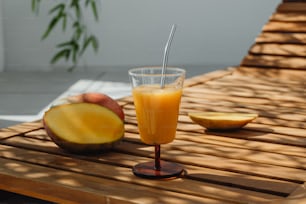 a glass of orange juice sitting on top of a wooden table