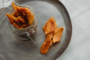 a glass jar filled with orange peels on top of a metal plate