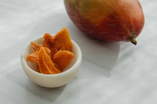 a white bowl filled with pieces of fruit next to a mango