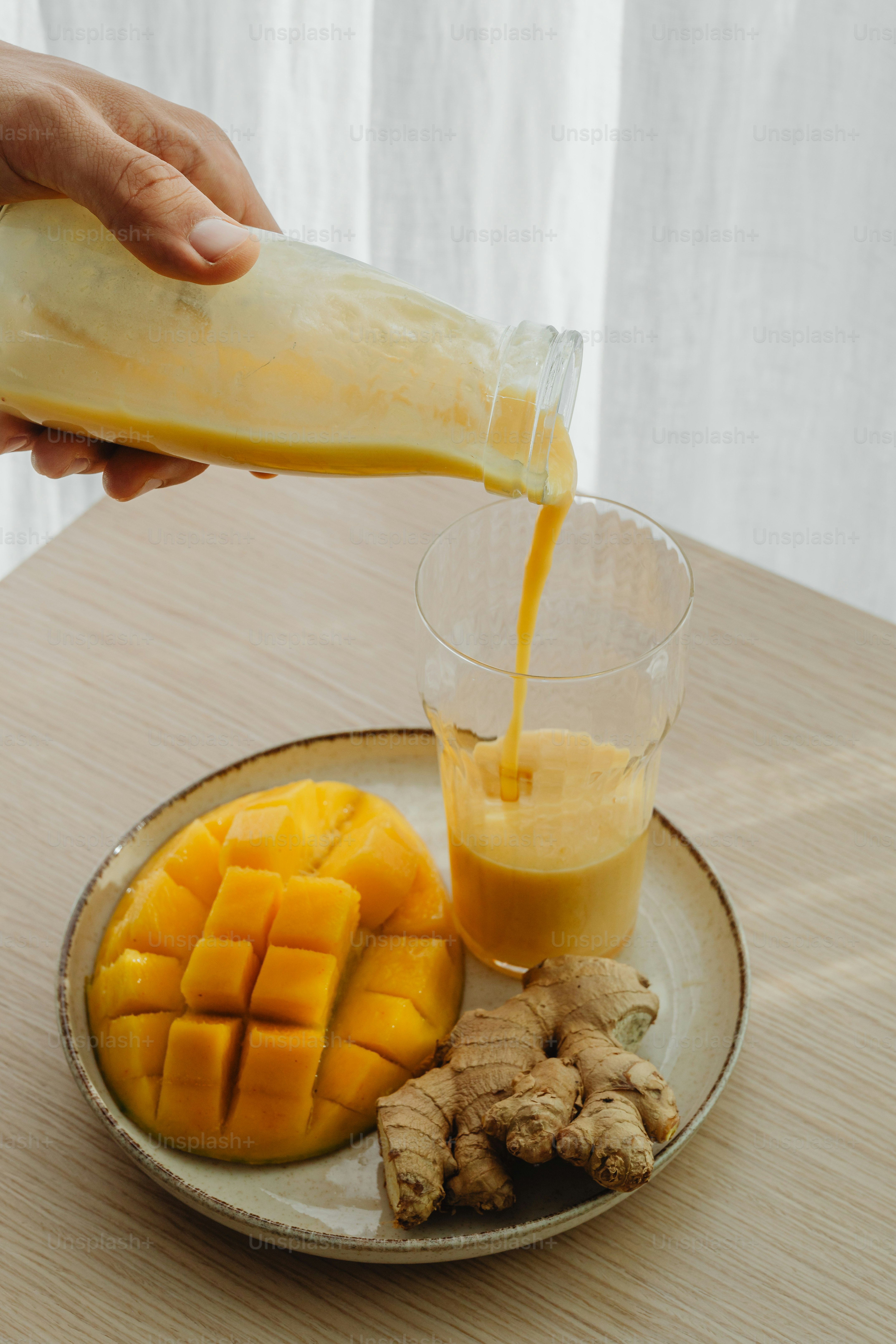 A wooden cutting board topped with mango slices next to a glass of