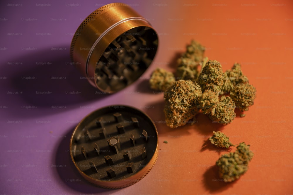 un molinillo y unos cogollos de marihuana sobre una mesa