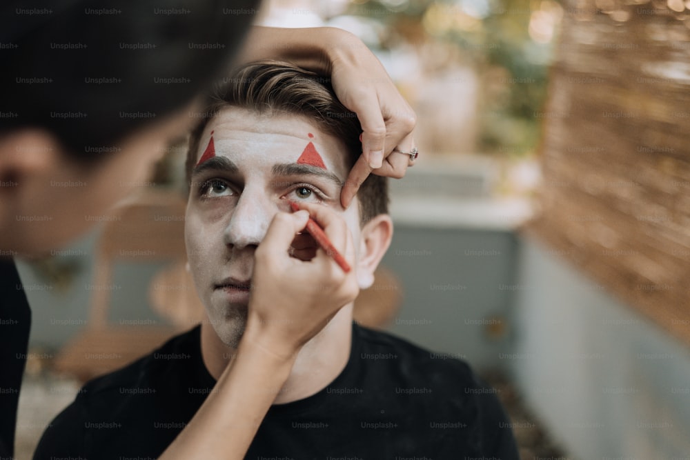 Un hombre se está pintando la cara con un triángulo rojo