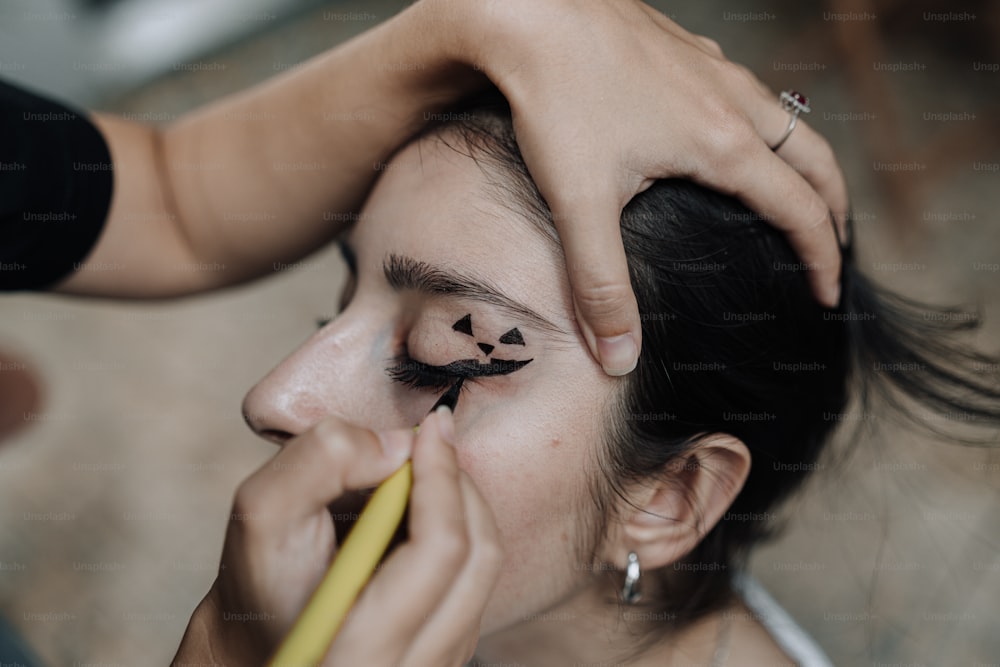 uma mulher está pintando as sobrancelhas