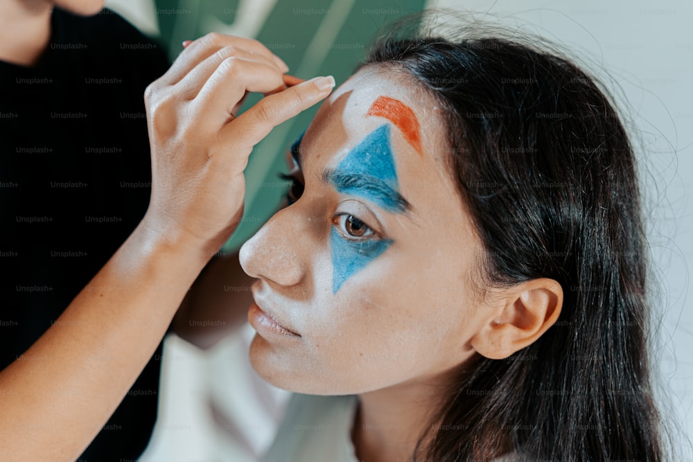a woman with blue and orange face paint on her face