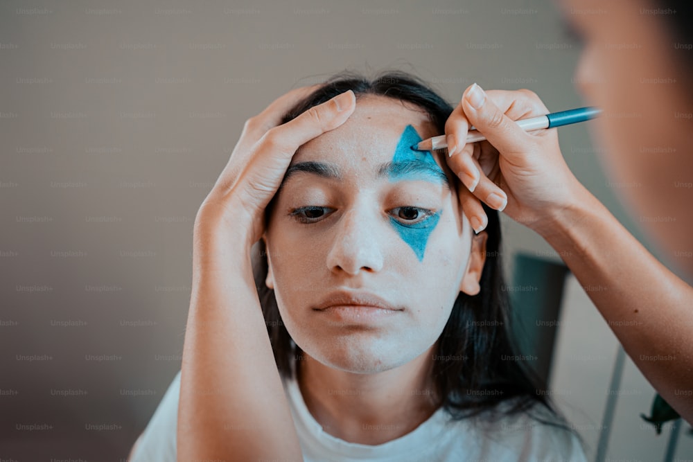 a woman getting her make up done with a blue marker