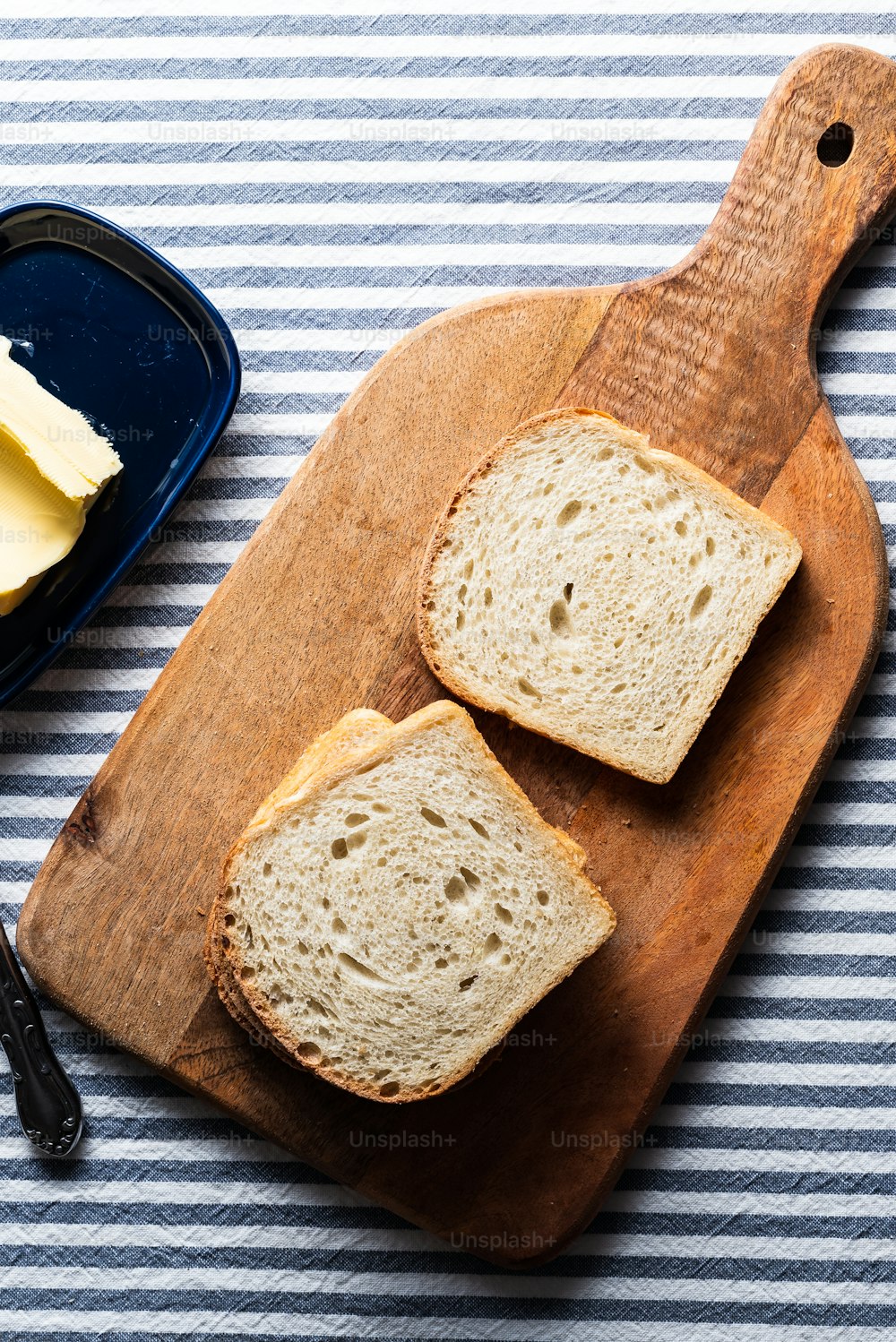 duas fatias de pão e manteiga em uma tábua de corte