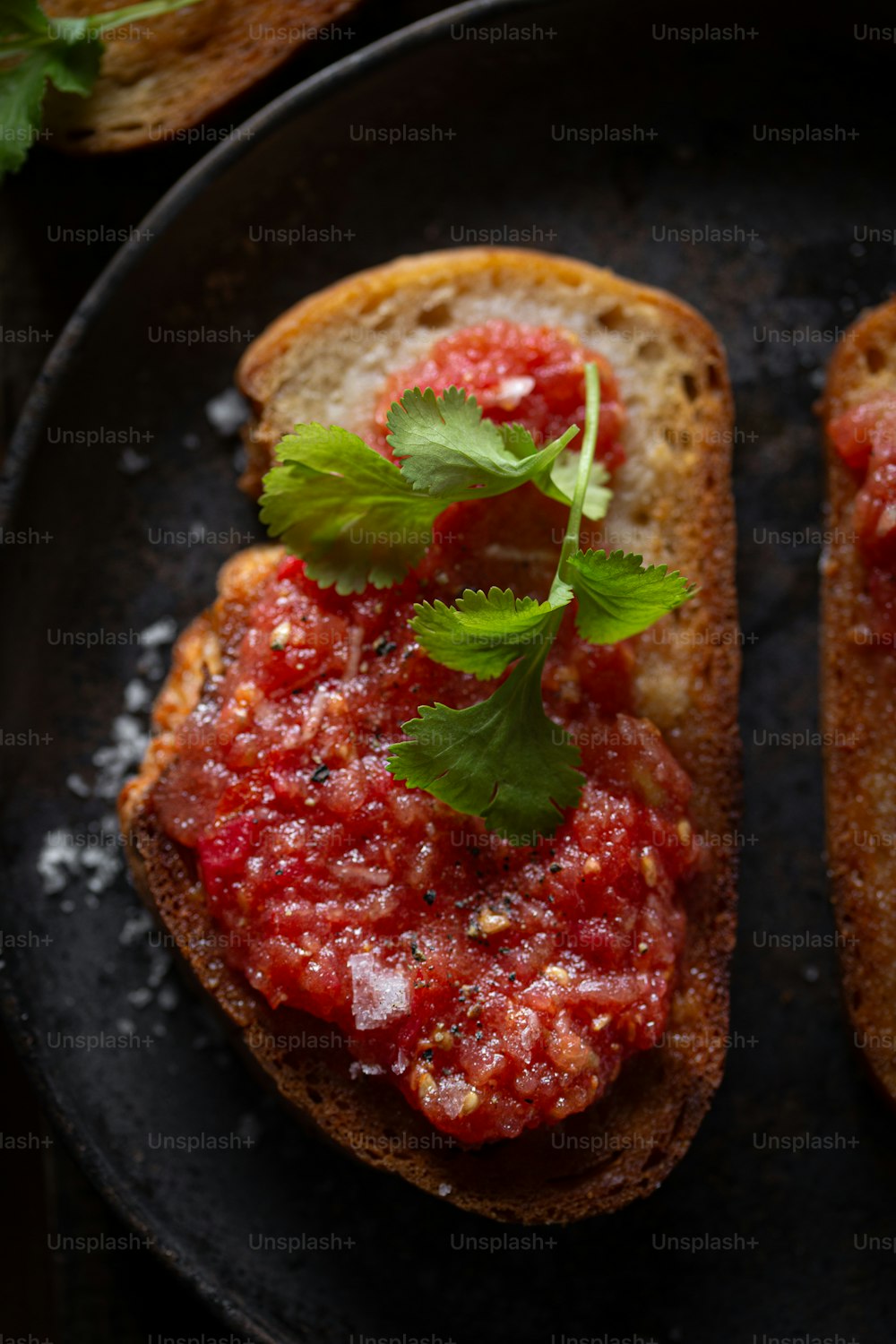 two pieces of bread with tomato sauce and parsley on top