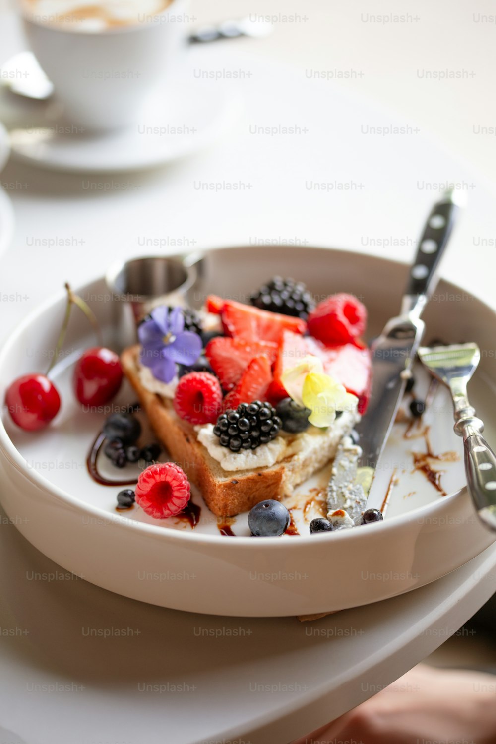 a white plate topped with a piece of cake covered in fruit