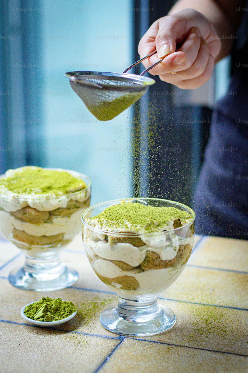 a person sprinkling green powder on top of a dessert