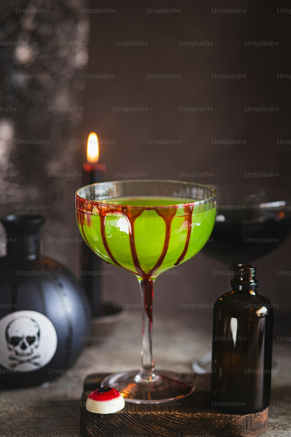 a green liquid in a glass next to a bottle of booze