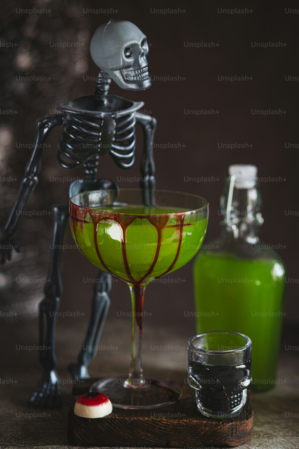 a skeleton sitting in a martini glass next to a bottle
