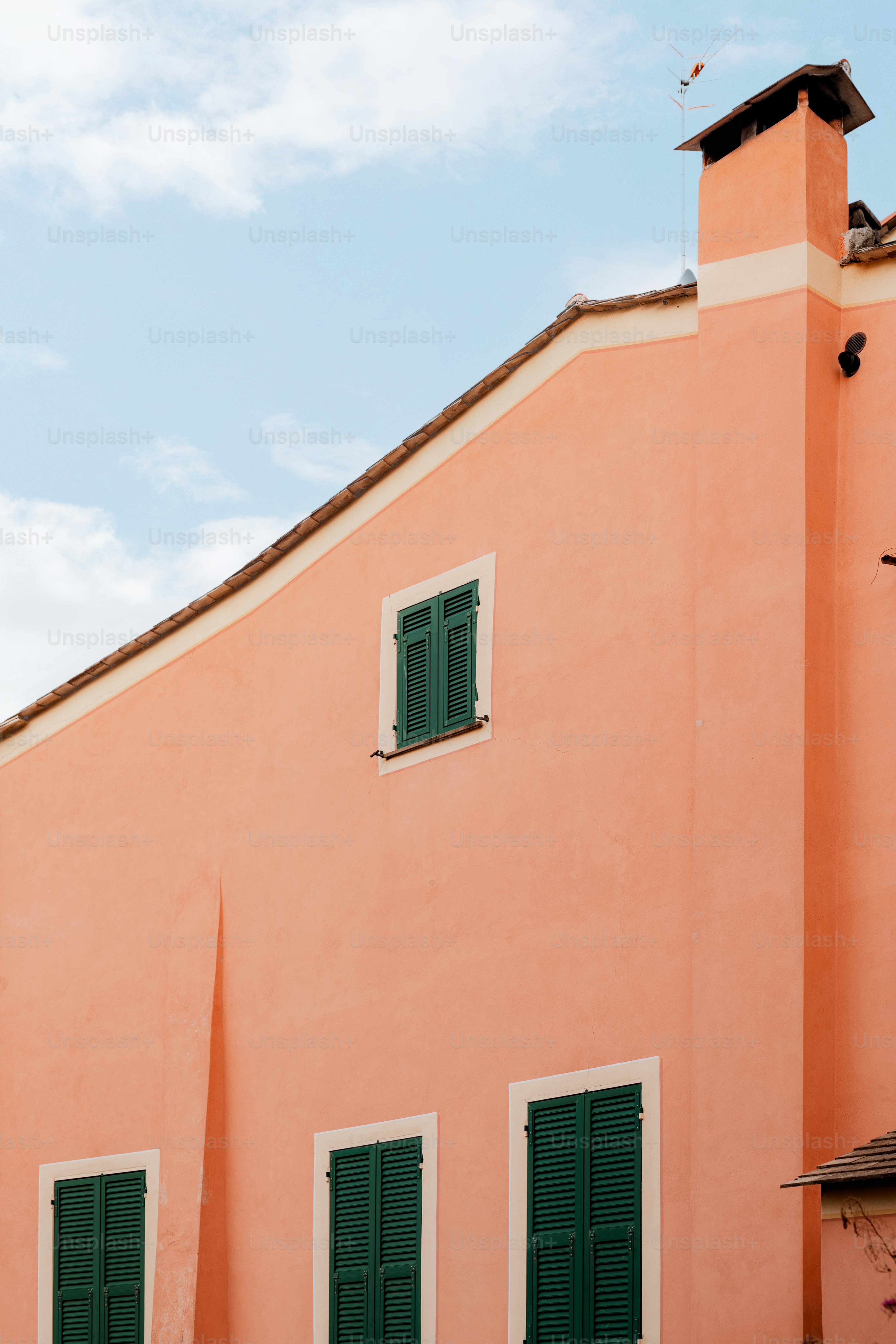 a pink building with green shutters and a clock tower