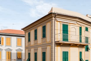 a tall building with green shutters and a balcony