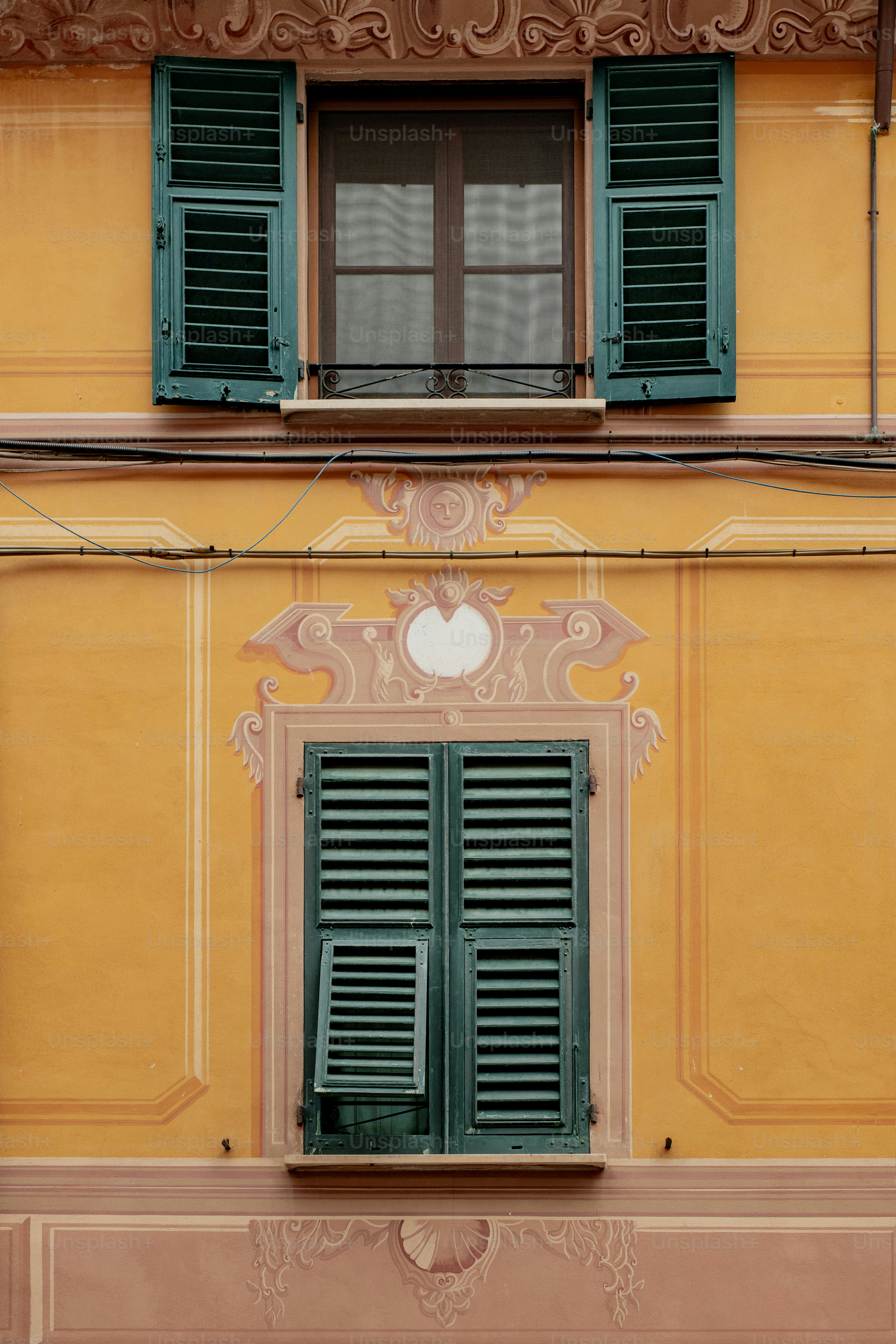 un edificio giallo con persiane verdi e un orologio