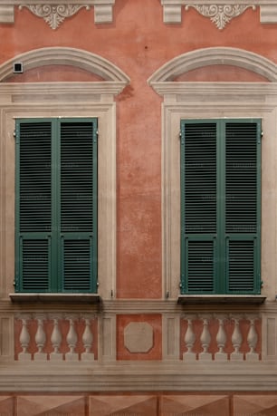 two windows with green shutters on a building