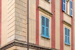 a red and tan building with blue shutters