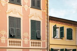 a building with green shutters and a clock in front of it