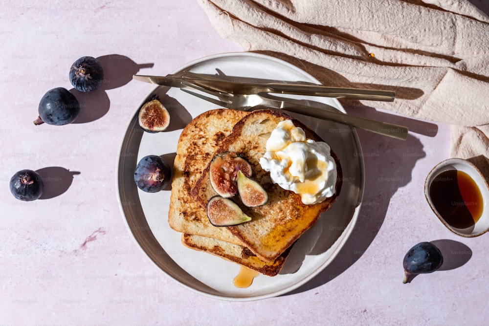 a plate of toast with figs and whipped cream