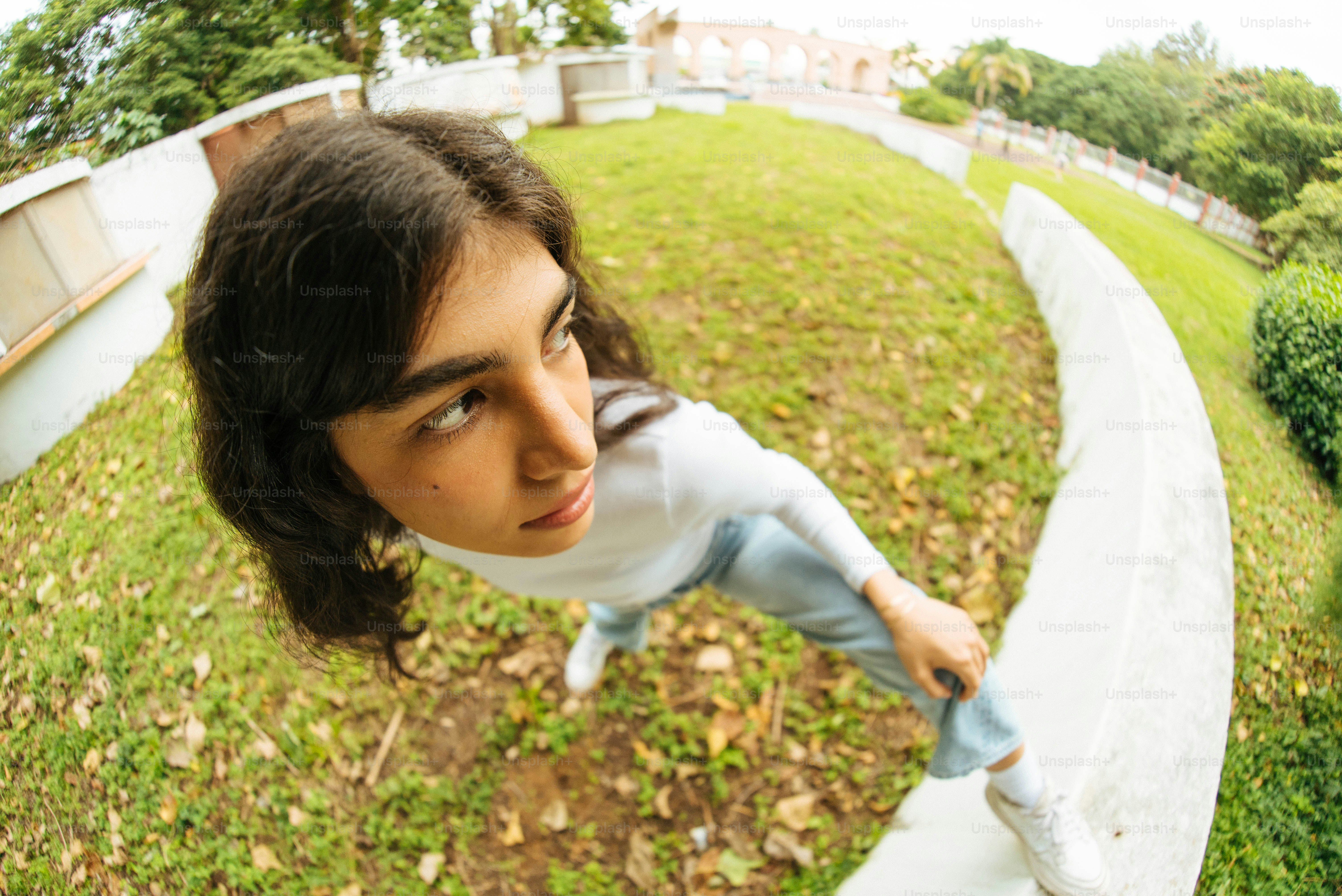 a young girl is standing on a ledge in a park