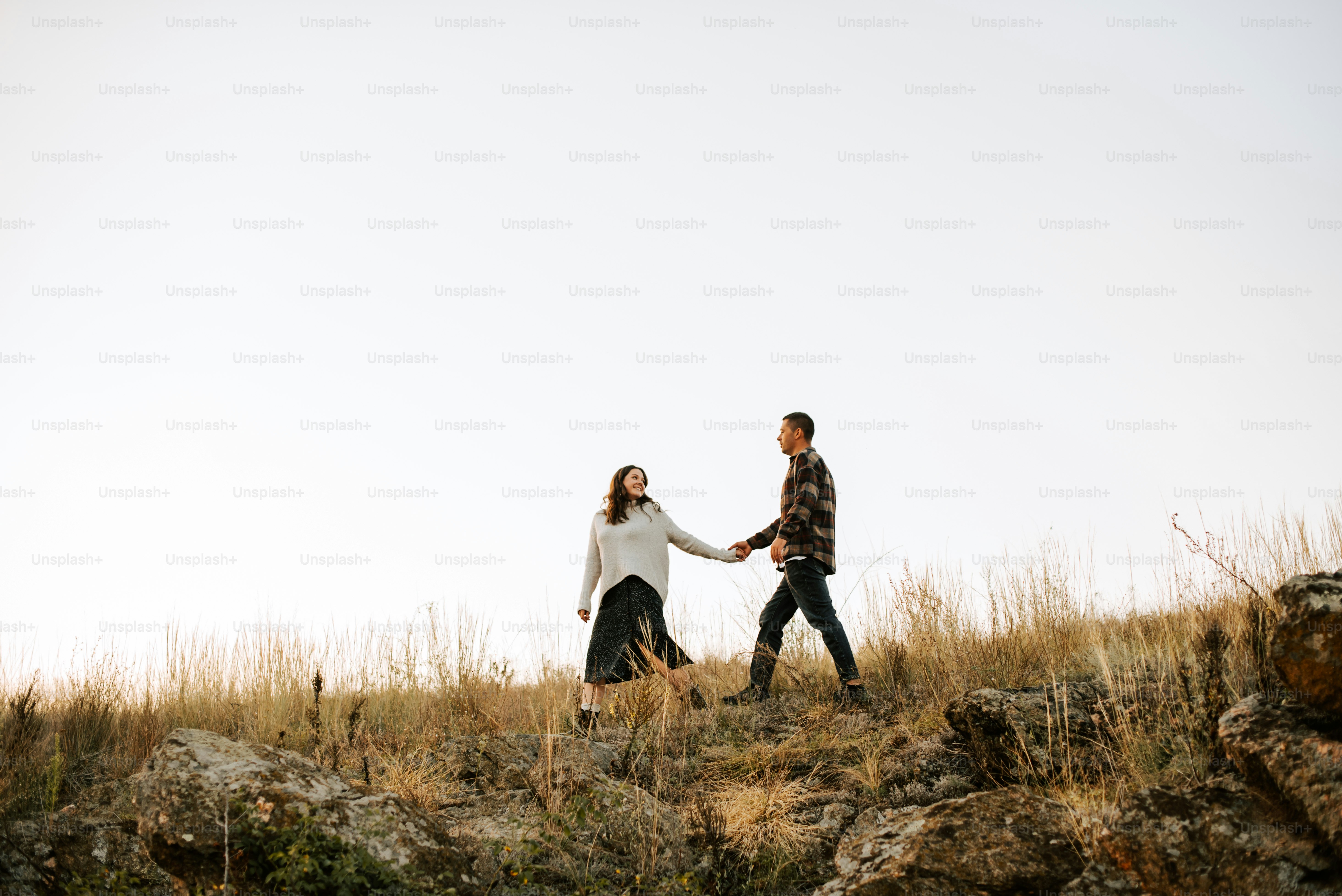 Un homme et une femme se tenant la main marchant à travers un champ