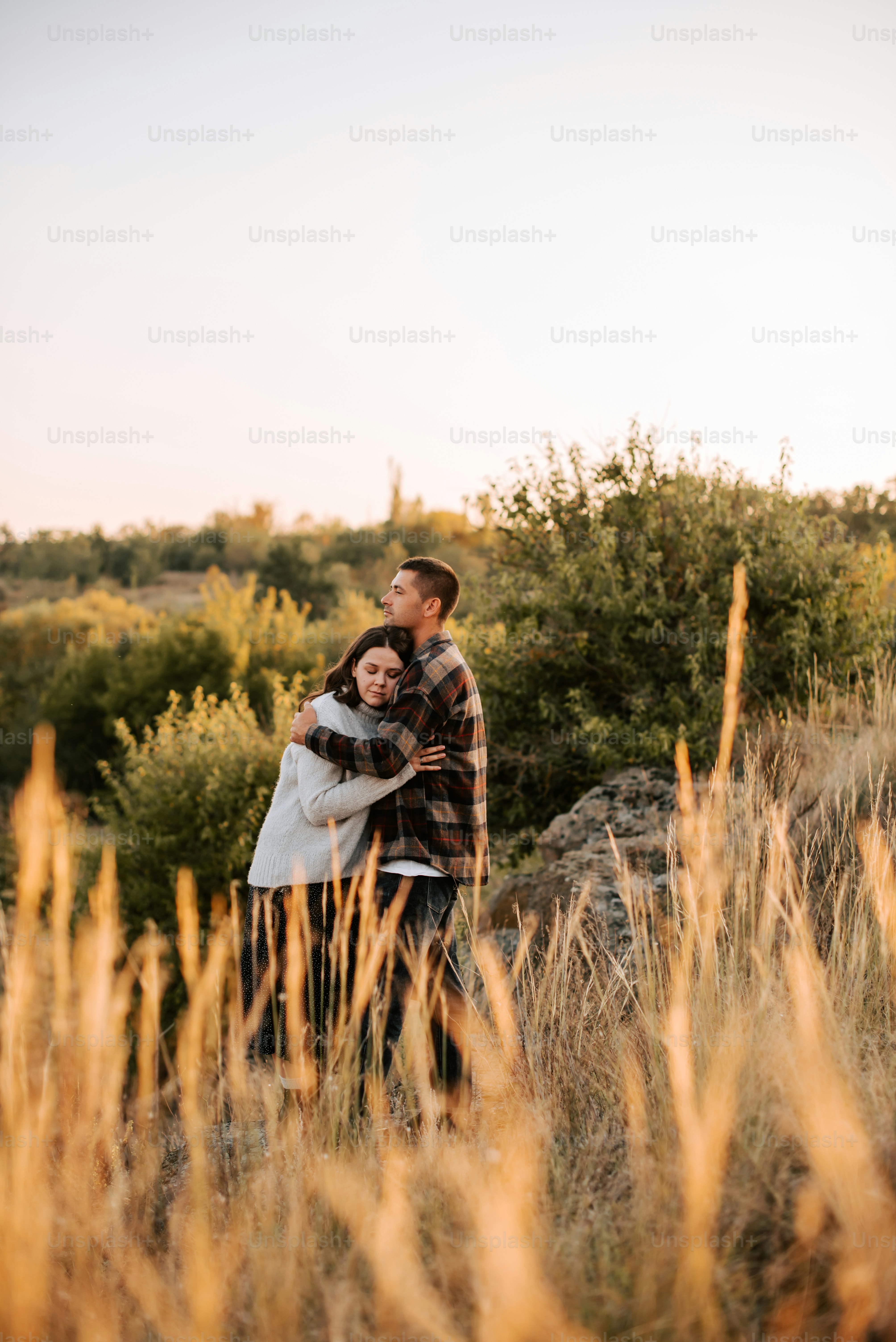 a man and woman embracing in a field of tall grass
